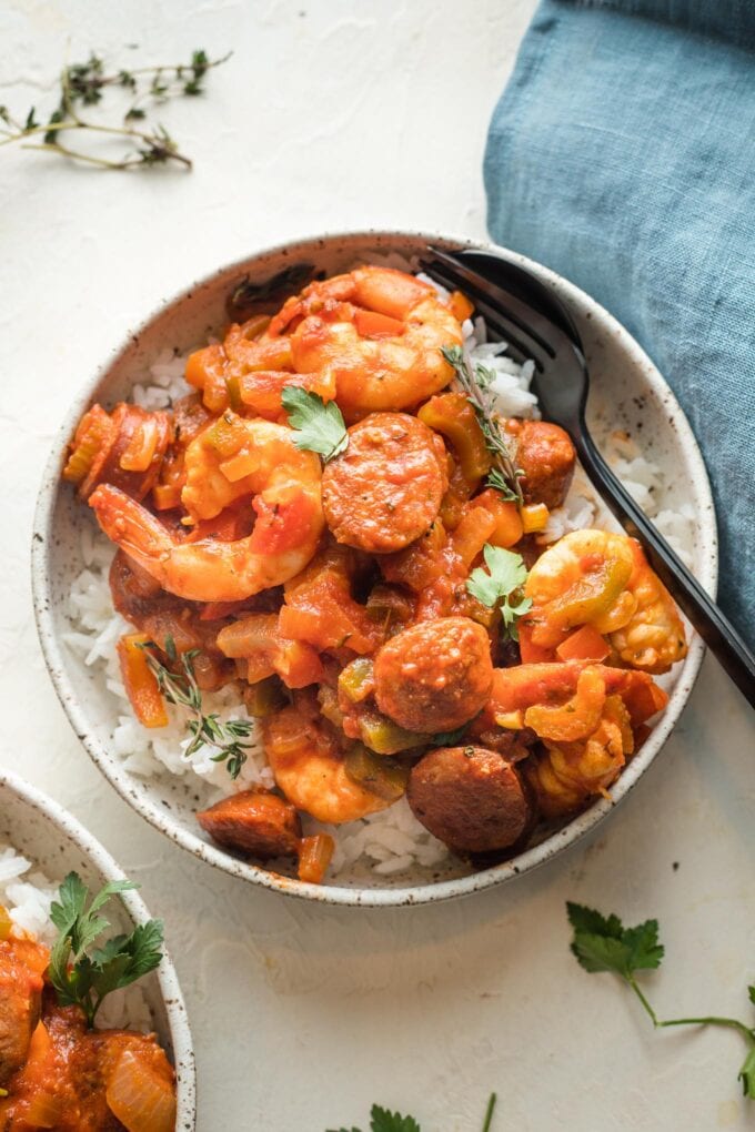 Small bowl with a bed of white rice and a shrimp sausage jambalaya spooned over top.