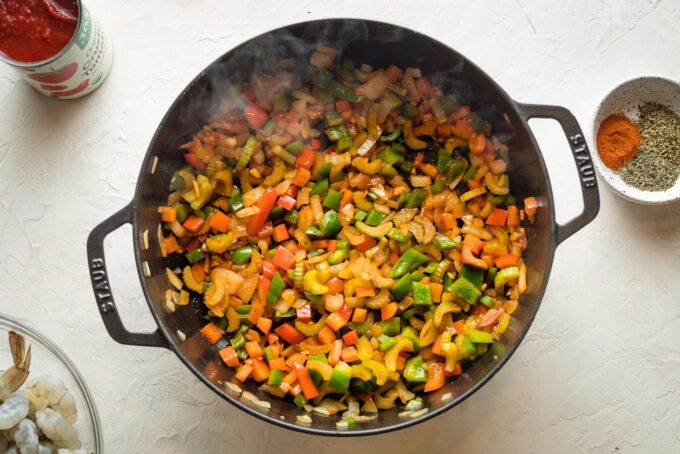 Peppers, onion, and celery cooking in a pan.