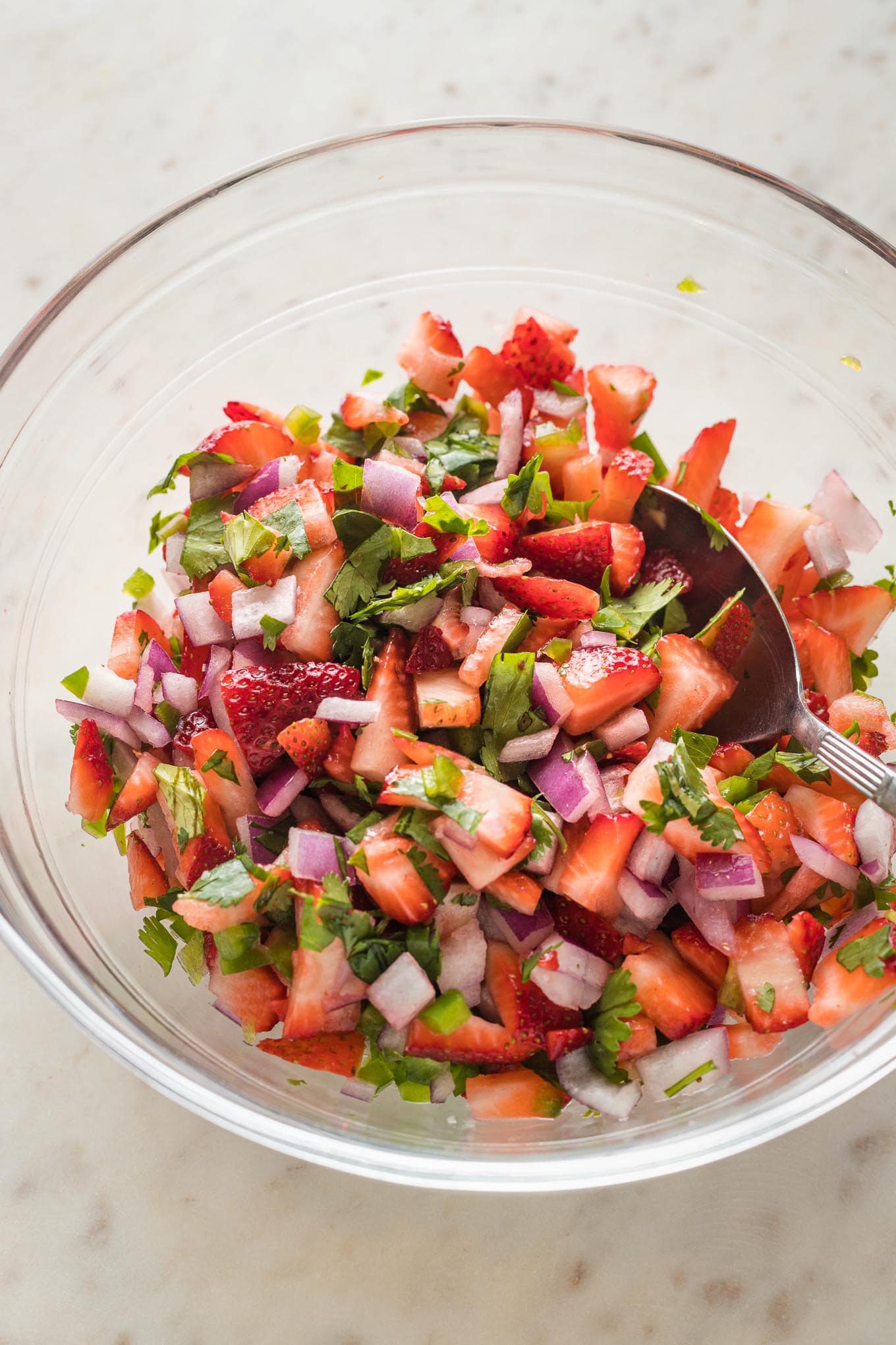 Close up of strawberry jalapeno salsa in a clear mixing bowl.