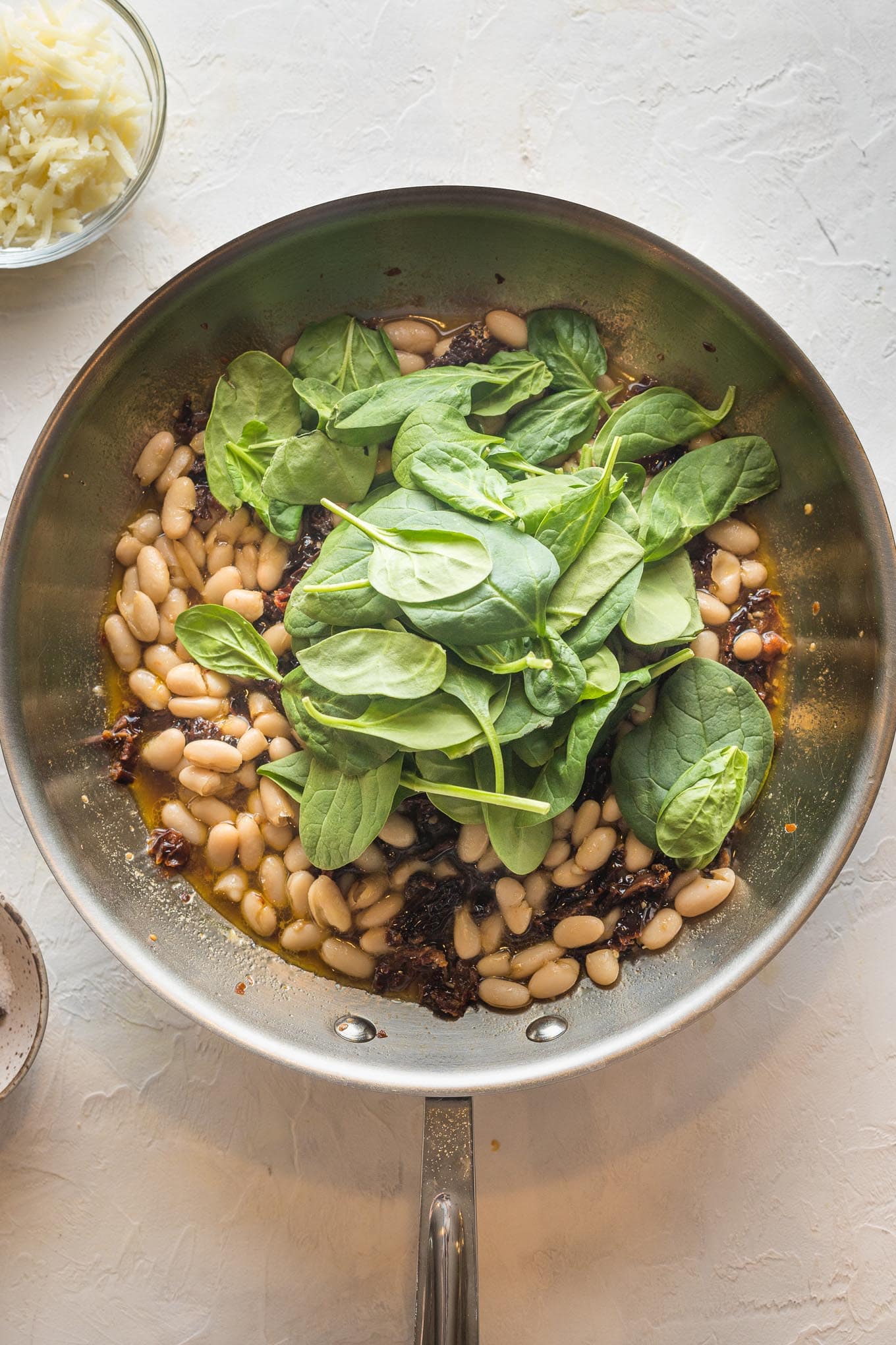 Spinach added to skillet with beans.