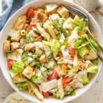 Large serving bowl filled with chicken Caesar pasta salad.