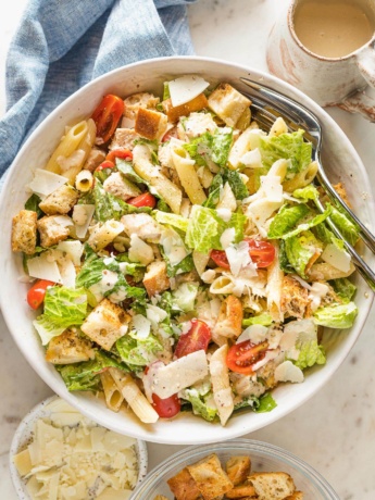 Large serving bowl filled with chicken Caesar pasta salad.