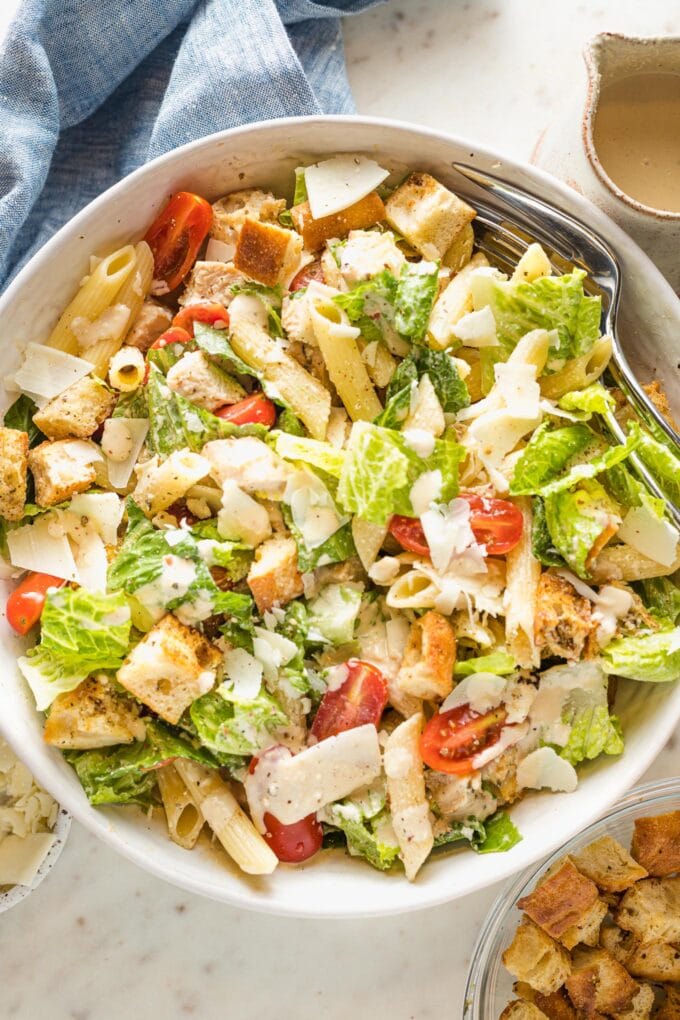 Large serving bowl filled with chicken Caesar pasta salad.