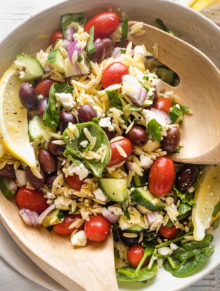 Close up of a lemon orzo salad tossed with feta, herbs, and veggies.