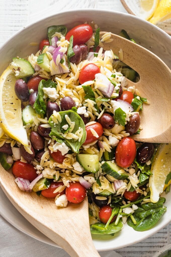 Close up of a lemon orzo salad tossed with feta, herbs, and veggies.
