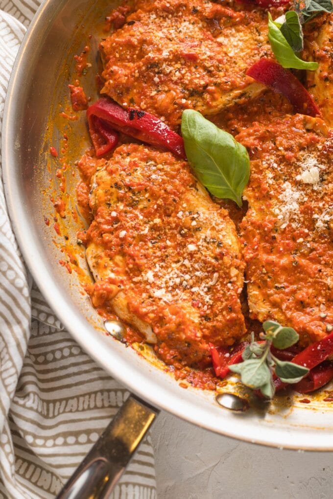 Close-up of a chicken breast coated in a creamy roasted red pepper sauce.