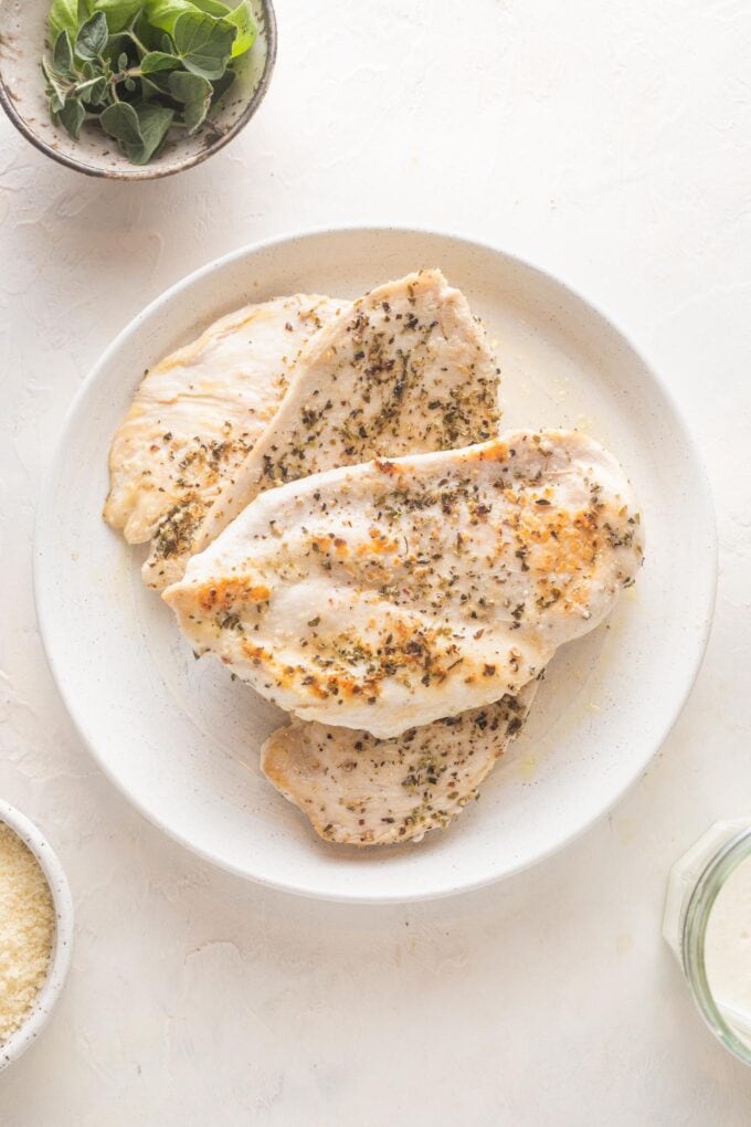 Browned chicken breasts resting on a white plate.