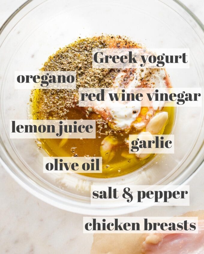 Prep bowl filled with Greek marinade ingredients: Greek yogurt, olive oil, red wine vinegar, lemon juice, garlic cloves, olive oil, salt, and pepper.