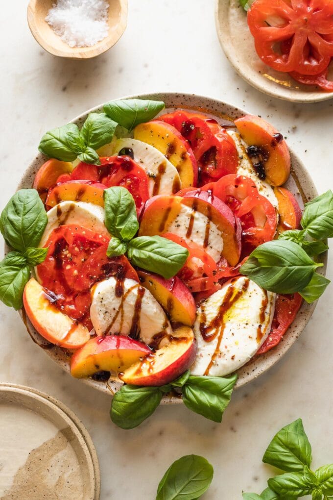 Plate with tomato, peach, and basil caprese.
