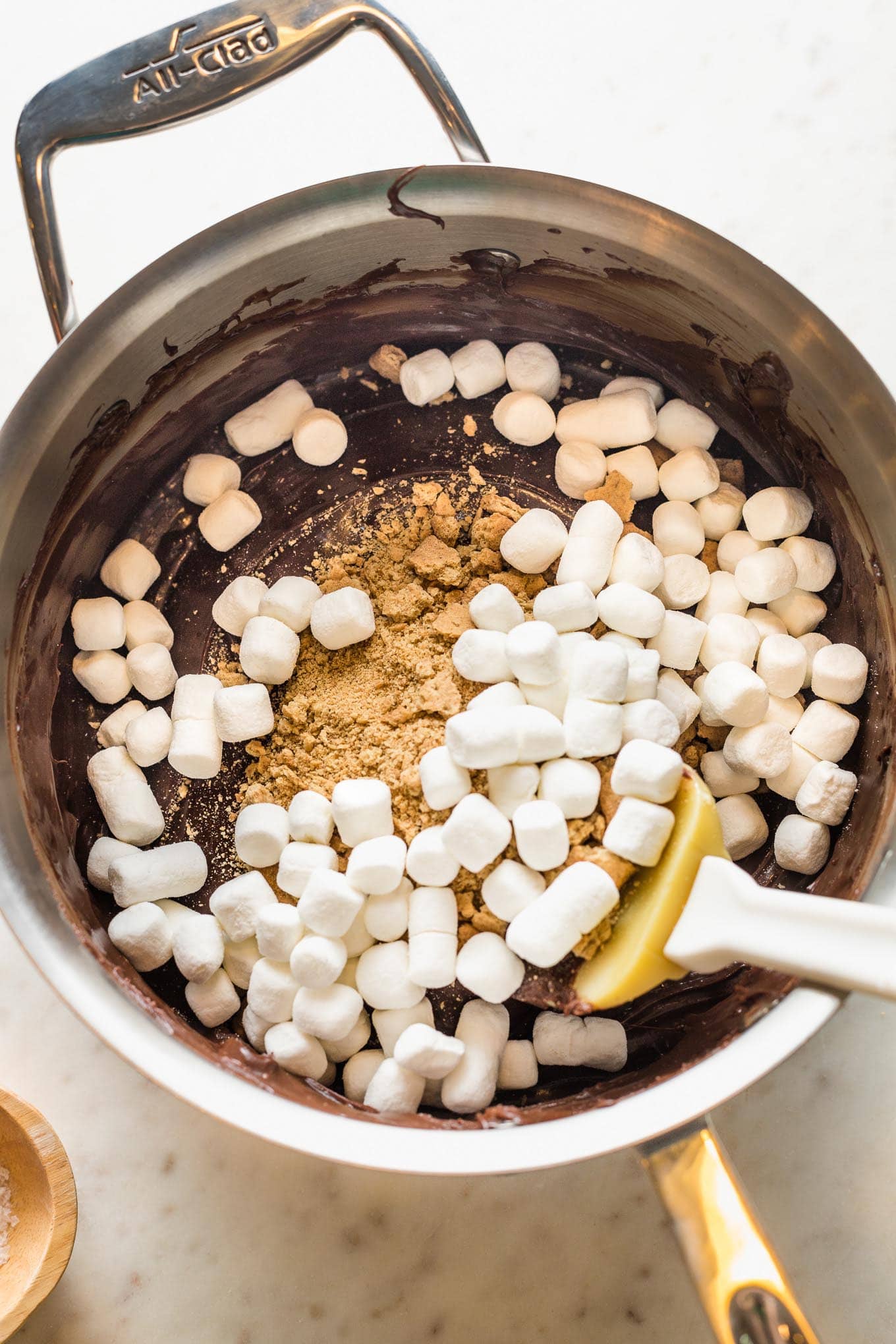 Crushed graham crackers and mini marshmallows added to melted chocolate in saucepan.