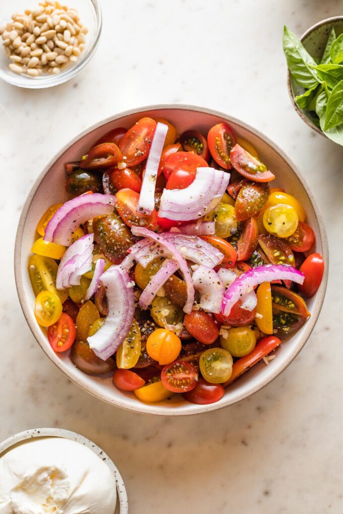 Tomatoes ready to marinate with red onion, garlic, olive oil, salt, and pepper.