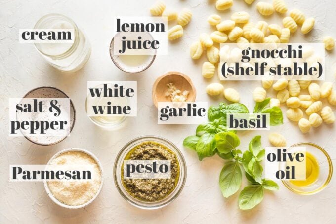 Labeled photo of prep bowls containing uncooked potato gnocchi, cream, lemon juice, garlic, white wine, Parmesan, pesto, garlic, basil, and olive oil.