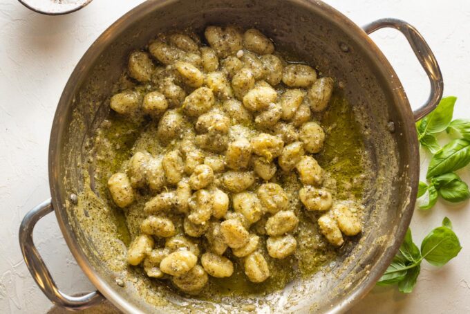 Creamy pesto gnocchi just cooked in a skillet.