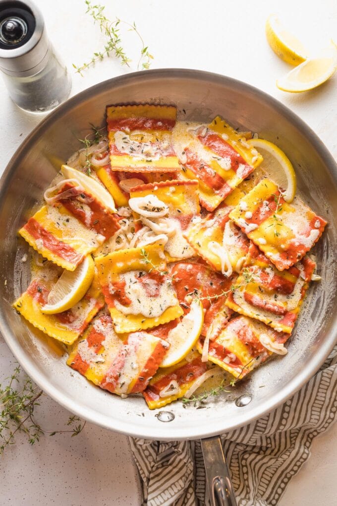 Skillet with striped lobster-filled pasta coated in a white wine and cream sauce.