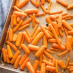 Roasted baby carrots on a large sheet pan.