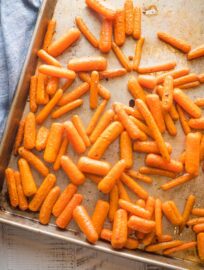 Roasted baby carrots on a large sheet pan.
