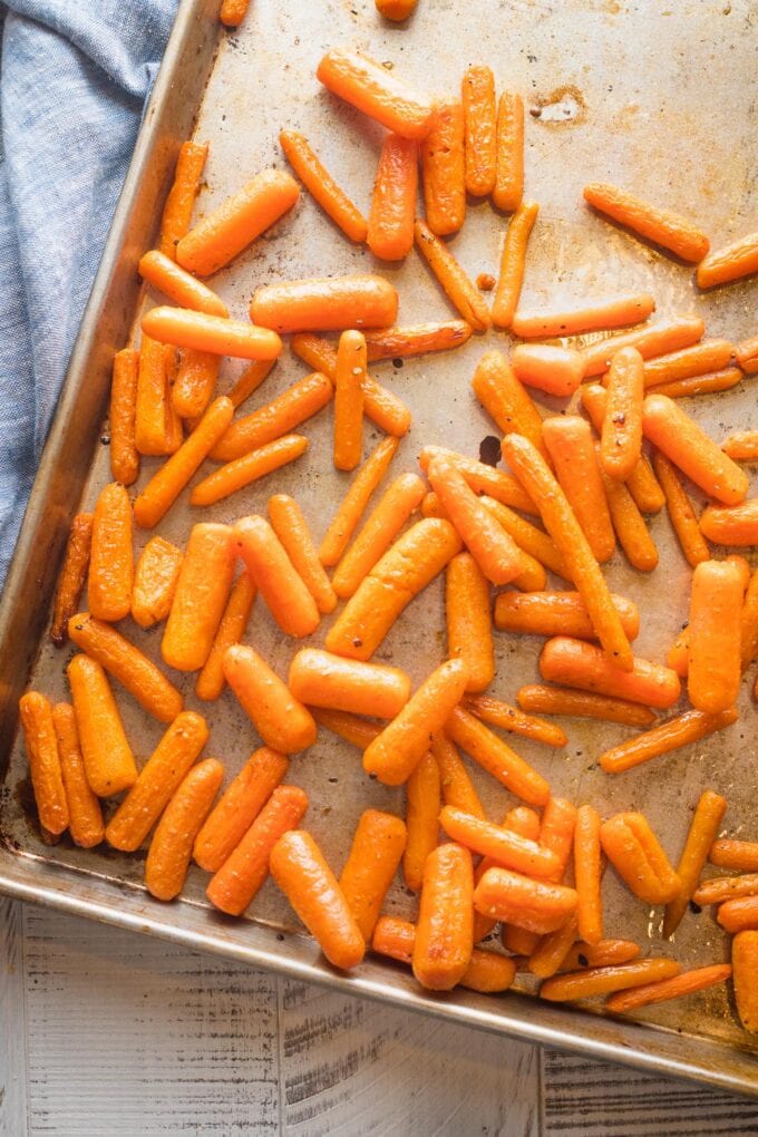 Roasted baby carrots on a large sheet pan.