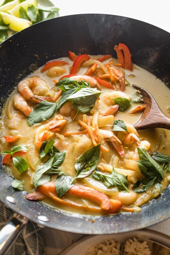 Thai green curry with veggies and shrimp cooked in a black wok.