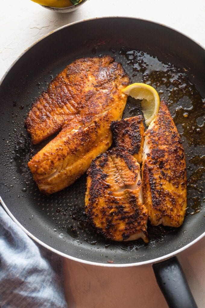 Blackened tilapia fillets cooked in a non-stick skillet.
