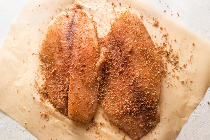 Spices rubbed into uncooked tilapia fillets.