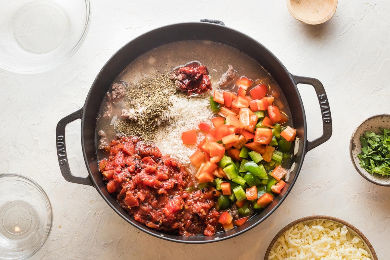 Tomatoes, rice, peppers, and seasoning added to pan.