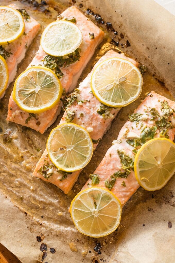 Close up of lemon herb salmon on a parchment lined baking sheet.