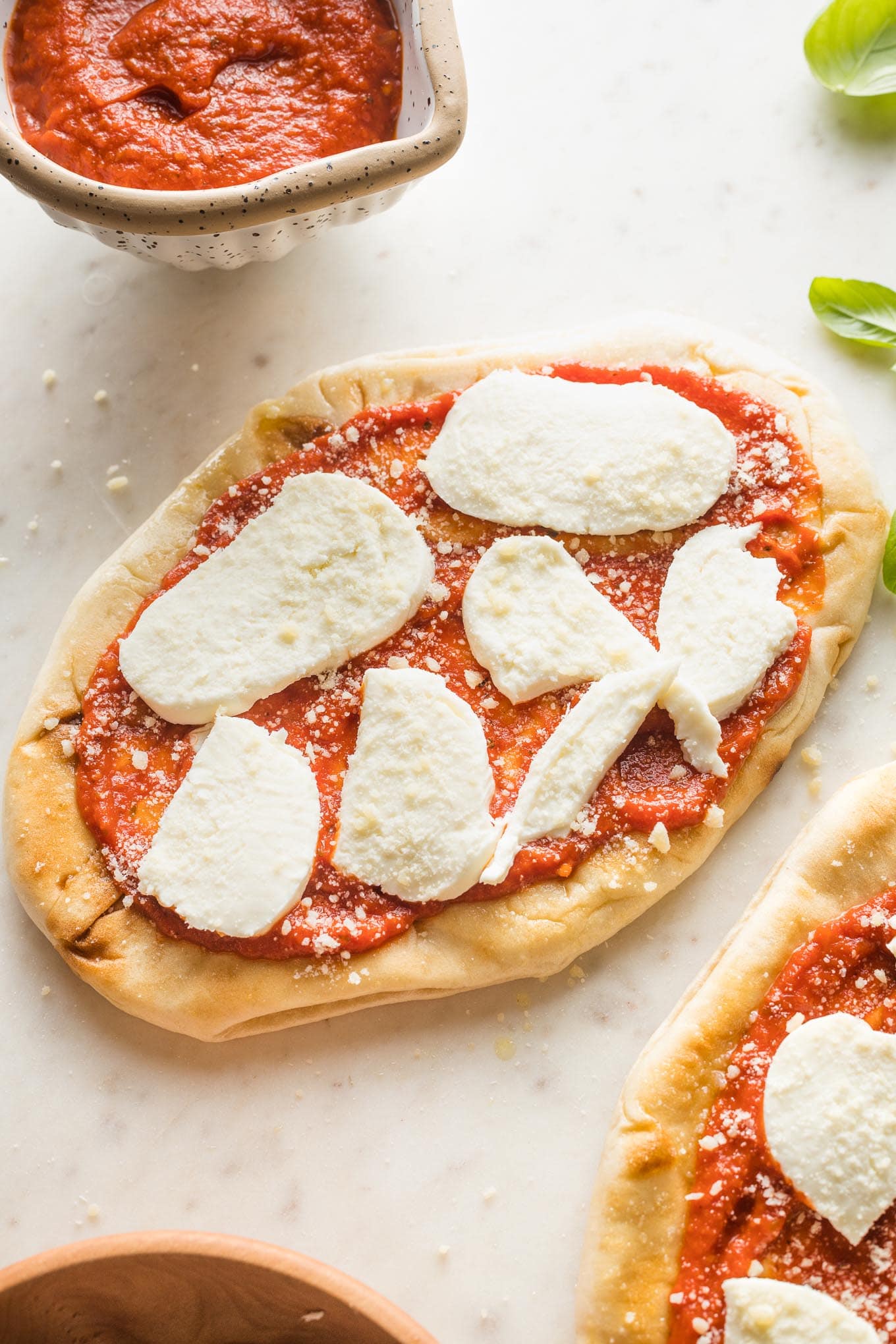 Naan pizzas topped with slices of mozzarella.