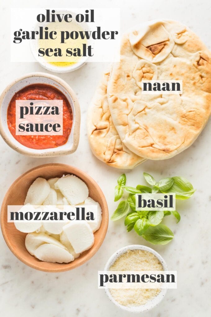 Photo of naan, fresh basil, olive oil, garlic powder, sea salt, pizza sauce, sliced mozzarella, and Parmesan.