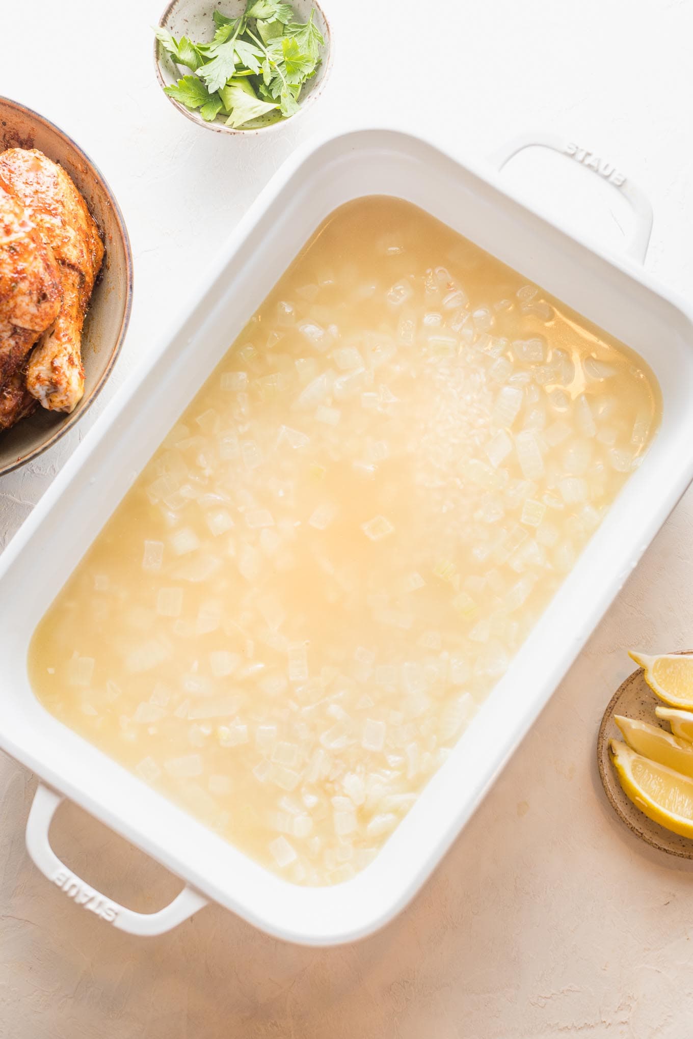 Just-boiled broth and water poured over rice in a large baking pan.