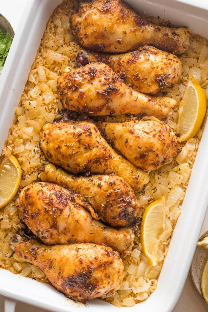 Close-up image of baked chicken legs cooked and served on a bed of rice.