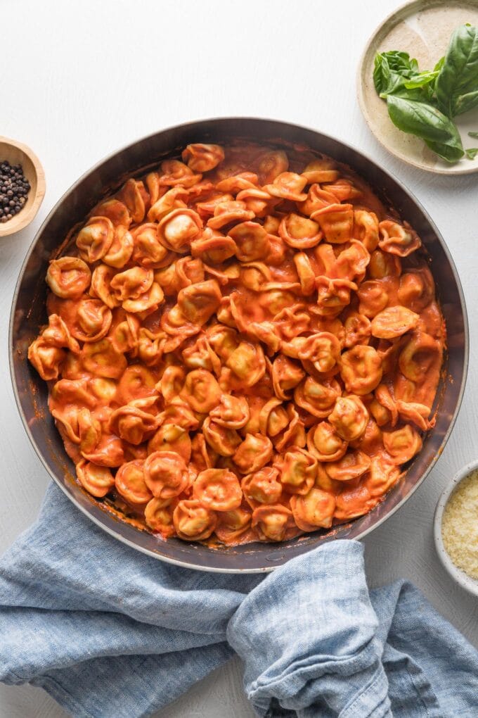 Overhead view of a skillet filled with a simple dish of creamy tomato tortellini.