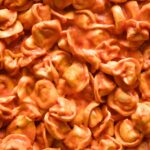 Close up view of cheese tortellini in a smooth tomato cream sauce.