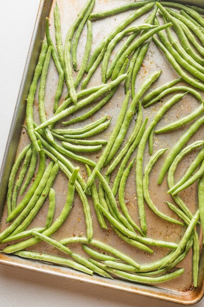 Rimmed sheet pan filled with uncooked green beans.