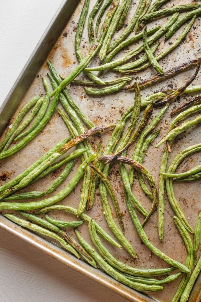 Rimmed sheet pan filled with roasted green beans.