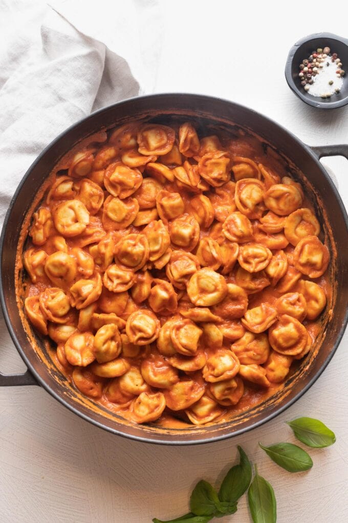 Tortellini cooked in a creamy tomato sauce in a cast iron skillet.