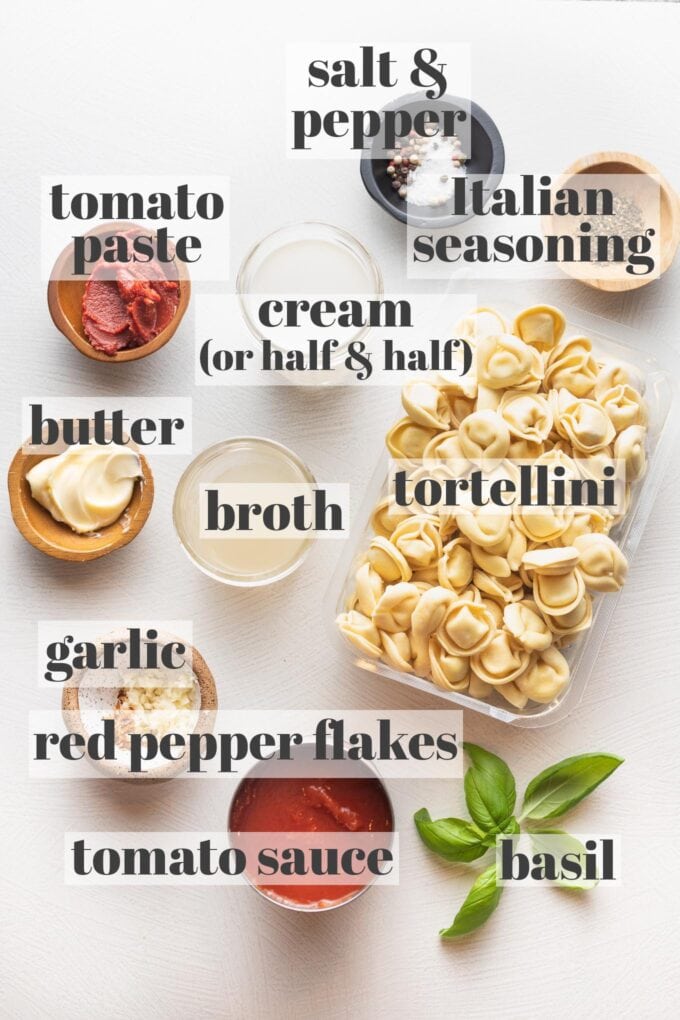 Refrigerated tortellini, cream, tomato paste and sauce, garlic, red pepper flakes, Italian seasoning, broth, and fresh basil arranged in prep bowls.