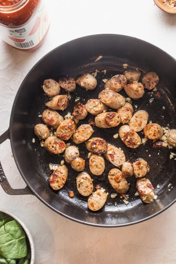 Chicken sausage sliced and browned in a large cast iron skillet.