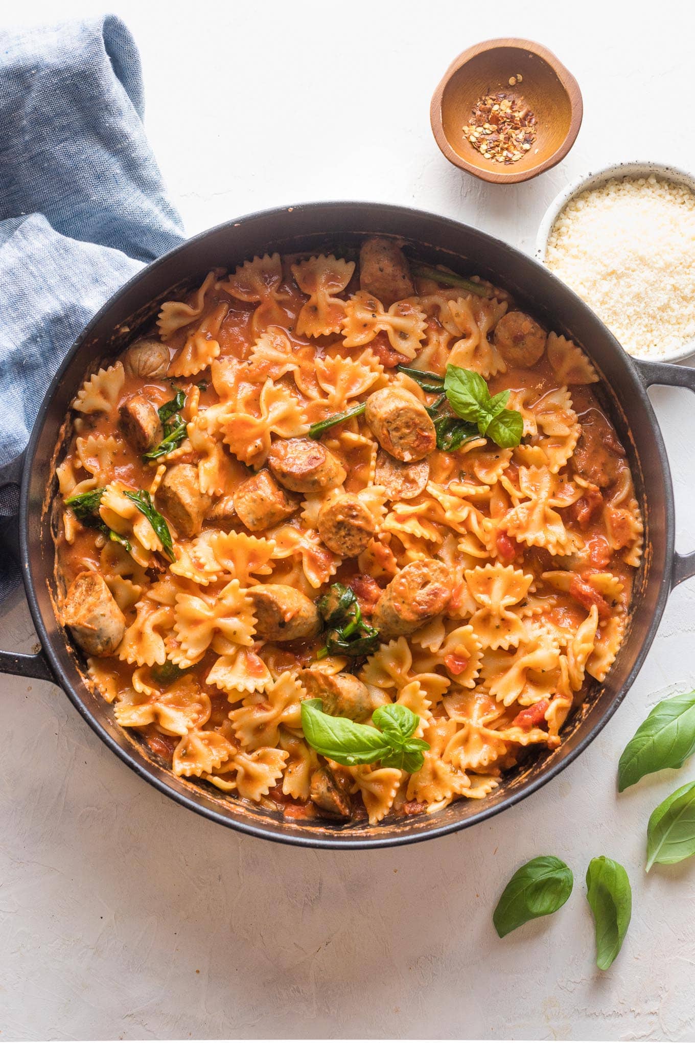 Scene with pasta and marinara sauce and Italian style chicken sausage, ready to serve from a large cast iron pan.