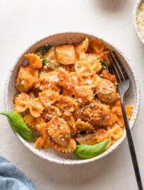 Bowl of Italian chicken sausage pasta garnished with parmesan and basil.