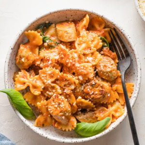 Bowl of Italian chicken sausage pasta garnished with parmesan and basil.