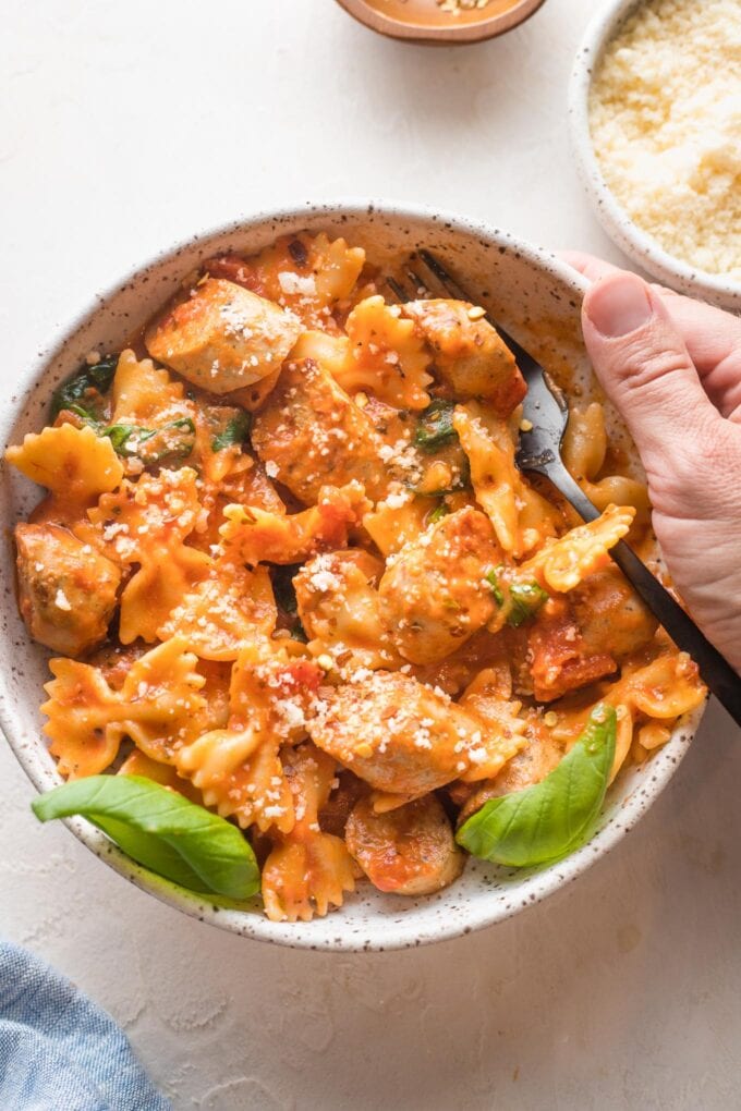 Bowl of Italian chicken sausage pasta garnished with parmesan and basil.