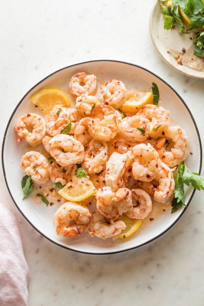 Plate full of cooked red Argentine shrimp served in a garlic lemon butter sauce.