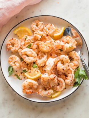 Plate full of cooked red Argentine shrimp served in a garlic lemon butter sauce.