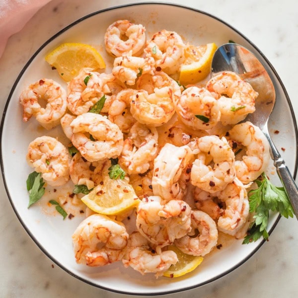 Plate full of cooked red Argentine shrimp served in a garlic lemon butter sauce.