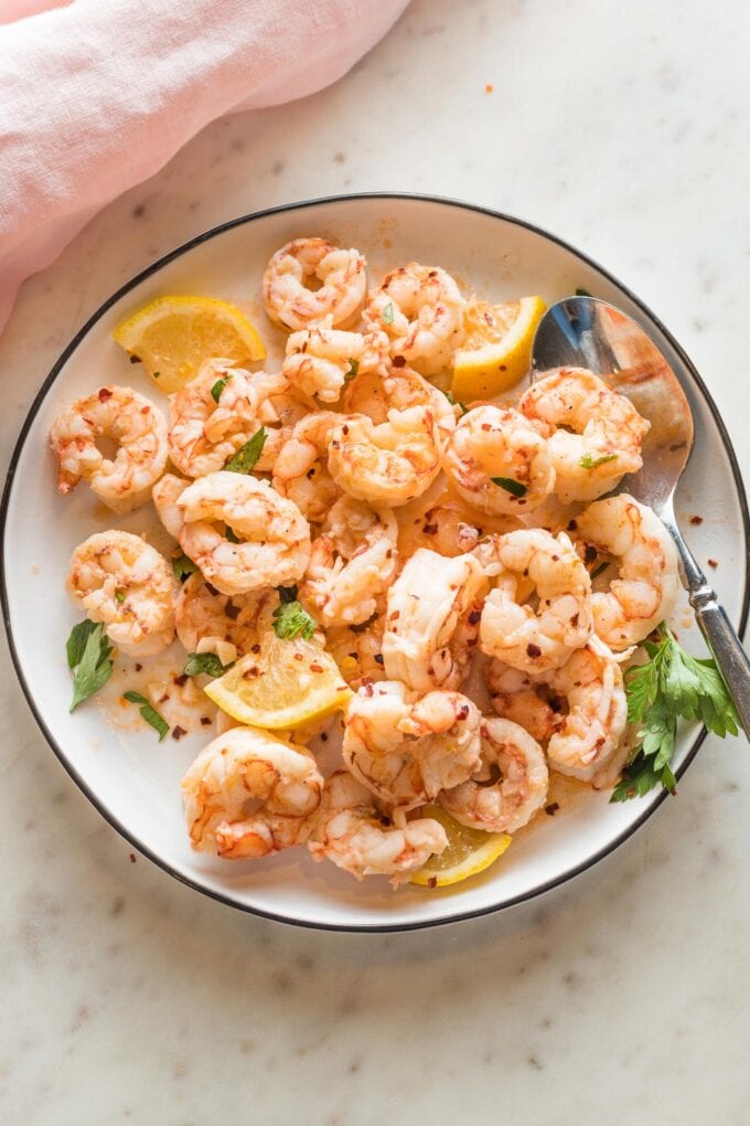 Plate full of cooked red Argentine shrimp served in a garlic lemon butter sauce.