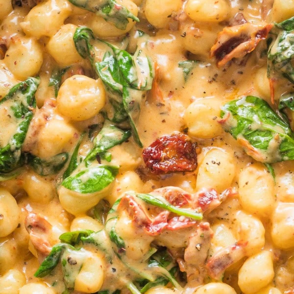 Close up creamy Tuscan gnocchi in a skillet.