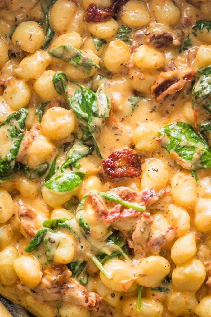 Close up creamy Tuscan gnocchi in a skillet.