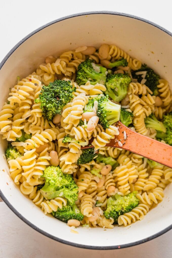 Dutch oven holding a one pot veggie pasta dish with white beans, broccoli, and lemon.