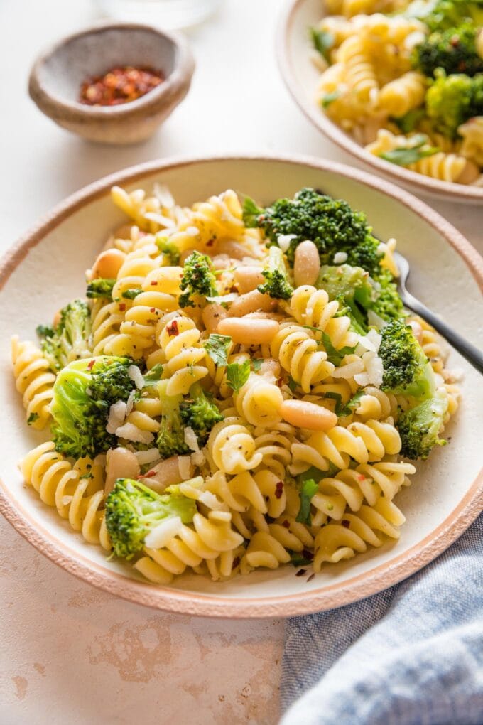 Close-up of a fork lifting a bite of veggie pasta.