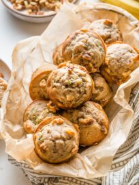 Basket full of banana zucchini muffins with walnuts.